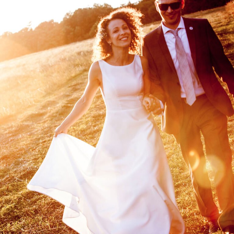 Esküvői pár természetes ragyogó mosollyal, zsebes menyasszonyi ruhában