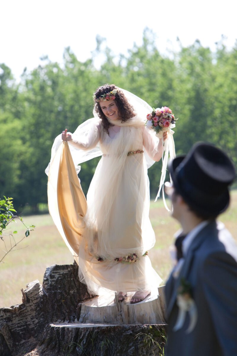 Regina egy kivágott fatörzsre áll fel, mint egy emelvényre, mindketten nevetnek